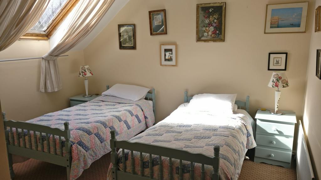 Twin bedroom, with two single beds, with numerous paintings on the wall.